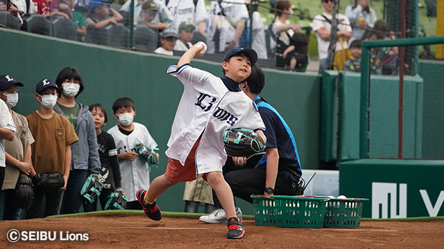 ドームでライオンズのユニフォームを着た少年がボールを投げている